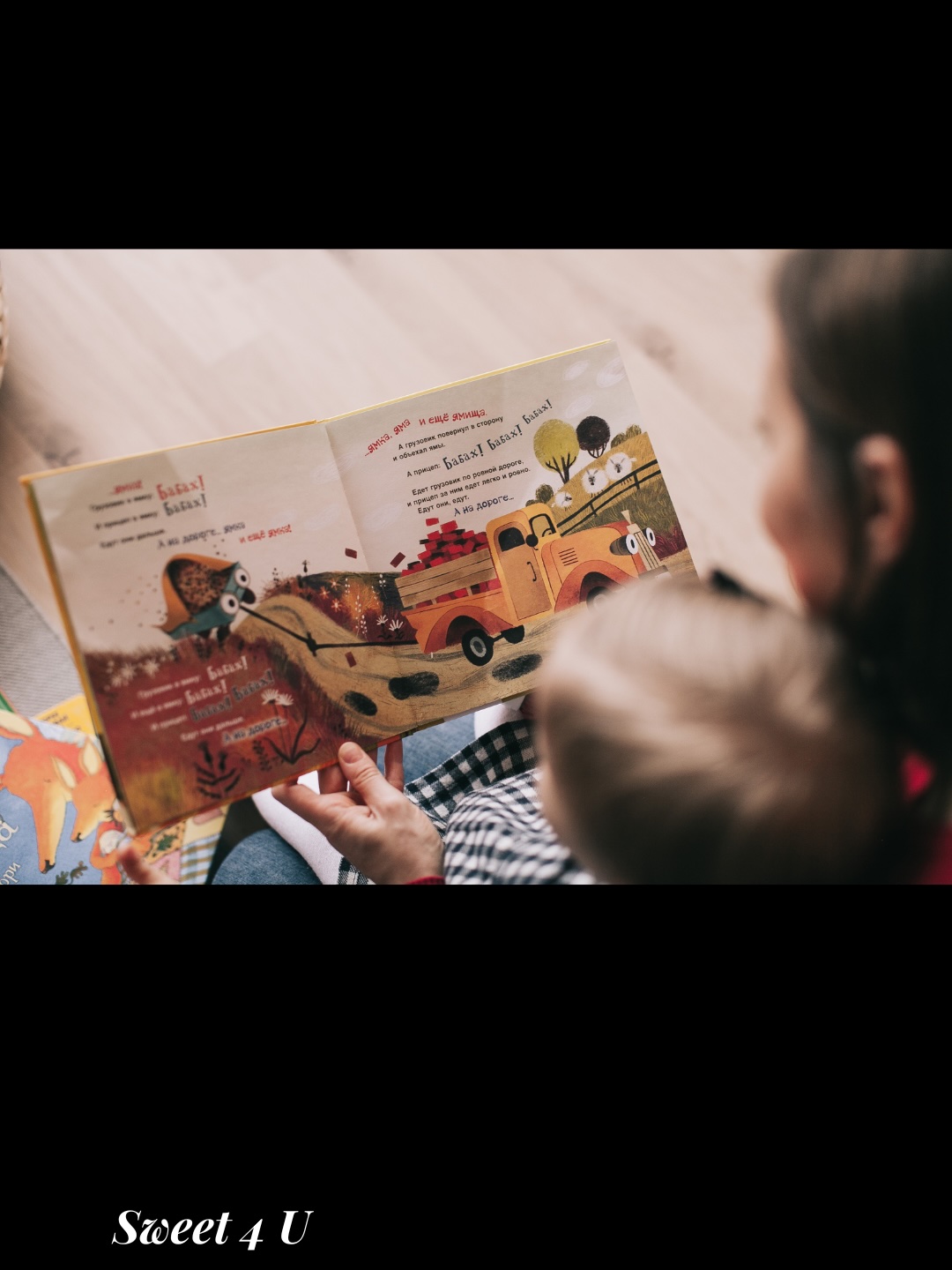 en premier plan une maman et son fils flouâtes qui lisent un livre histoire du soir